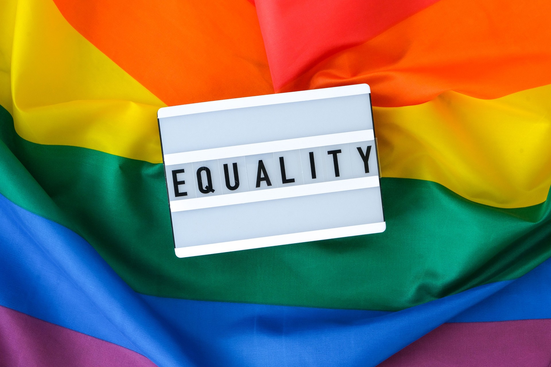 Rainbow flag with lightbox and text EQUALITY. Rainbow lgbtq flag made from silk material. Symbol of LGBTQ pride month. Equal rights. Peace and freedom